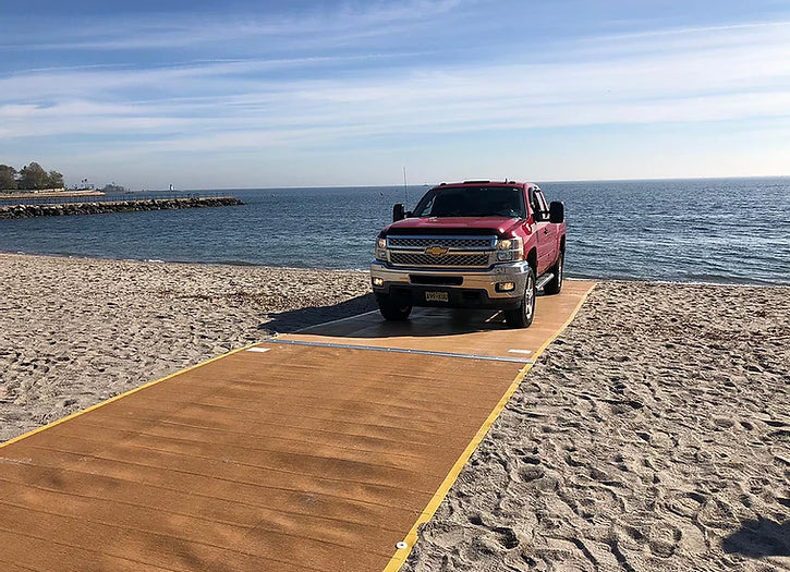 Red Truck Driving Up The Beach On A  AccessRec Mustmove® Vehicle Beach Access Mat