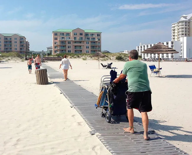 Man Pushing A Beach Gear Stroller Down An  AccessRec Mr Boardwalk Beach Access Mat 