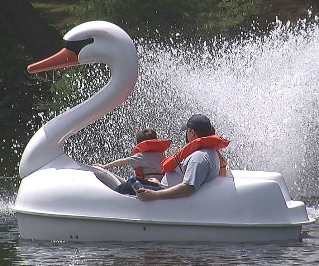two adults and one kid having fun in the Adventure Glass Swan Classic 2 Person Paddle Boat
