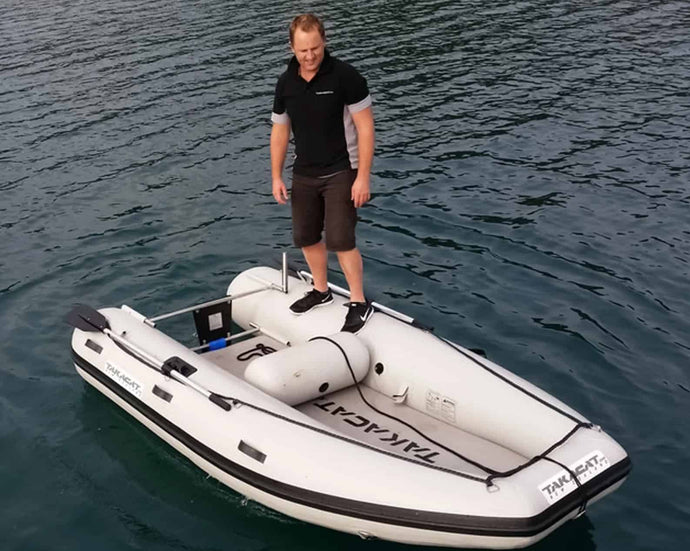 Man standing at the side of the Takacat T380S Inflatable Boat