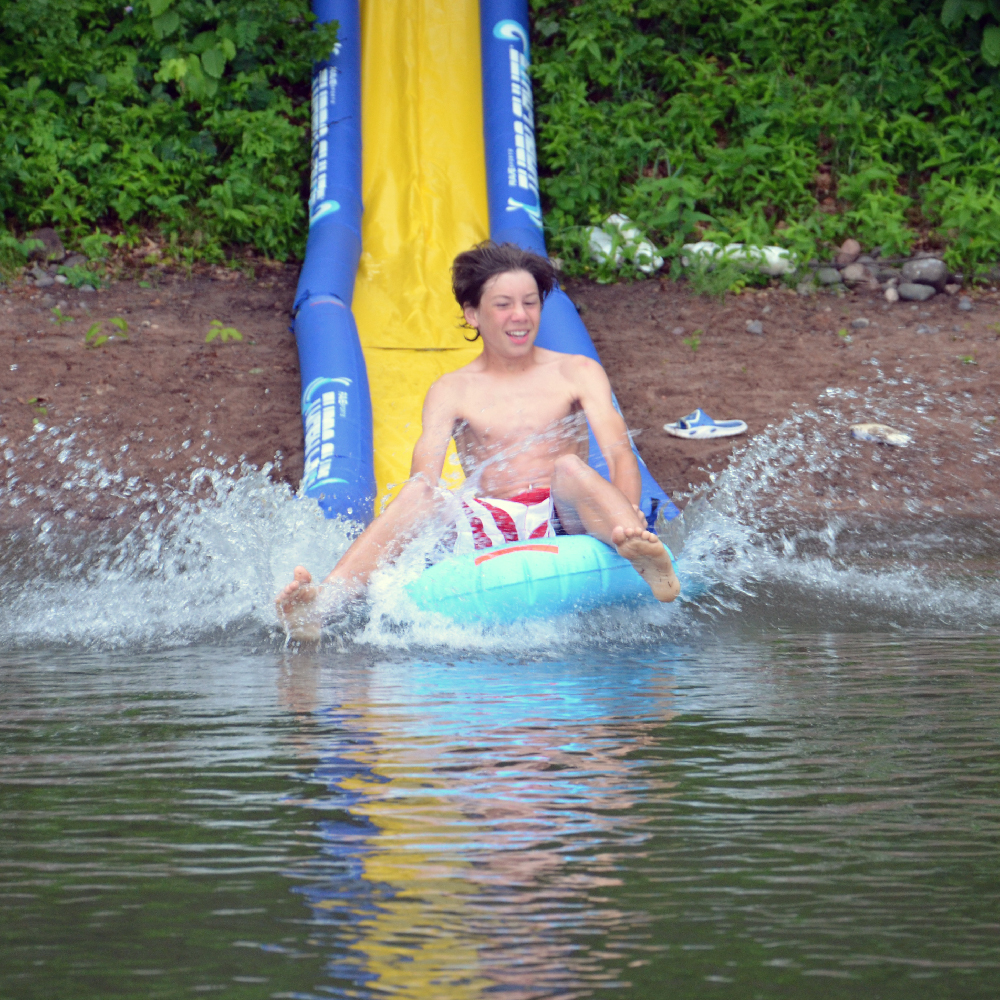 A kid riding at the Turbo Sled while sliding in the Rave 20' Turbo Chute Waterslide