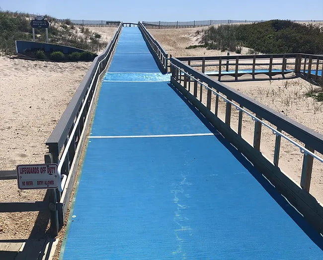 Blue  AccessMat® Beach Accessibility Mats  connected together to make a walkway across the sand           