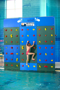 a girl climbing the Spectrum Aquatics Kersplash Challenger Pool Climbing Wall blue-green