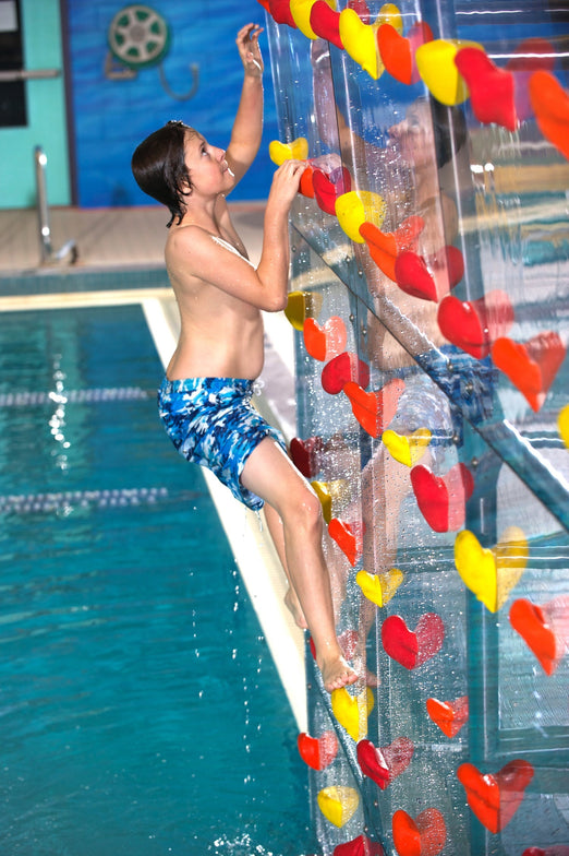 a boy climbing the Spectrum Aquatics Kersplash Challenger Pool Climbing Wall crystal at the side of the pool