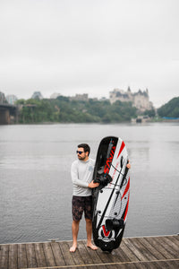 Man standing beside the SAVA All-New E1-B Electric Surfboard black red