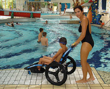 Load image into Gallery viewer, Lady pushing a child using a Hippocampe Swimming Pool Wheelchair