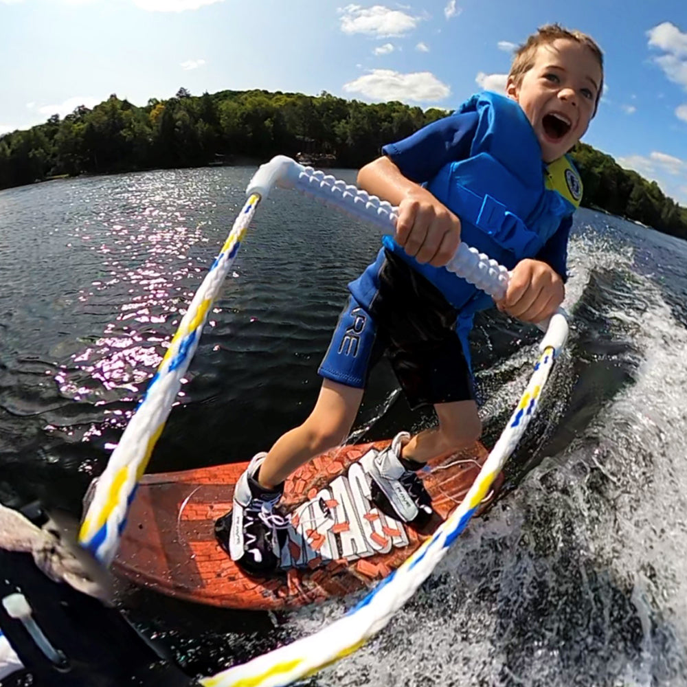 Rave Impact™ Red Brick wakeboard with Youth bindings with a boy riding on it.