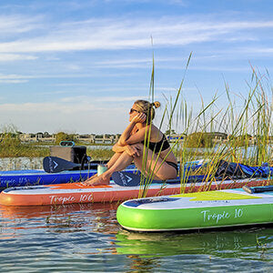 a woma seating on Pulse The Tropic 10.6 ft Inflatable Stand Up Paddleboard