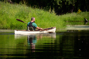 Man paddling with the Merrimack Canoes Solitaire 11'9" Solo Canoe at the lake.