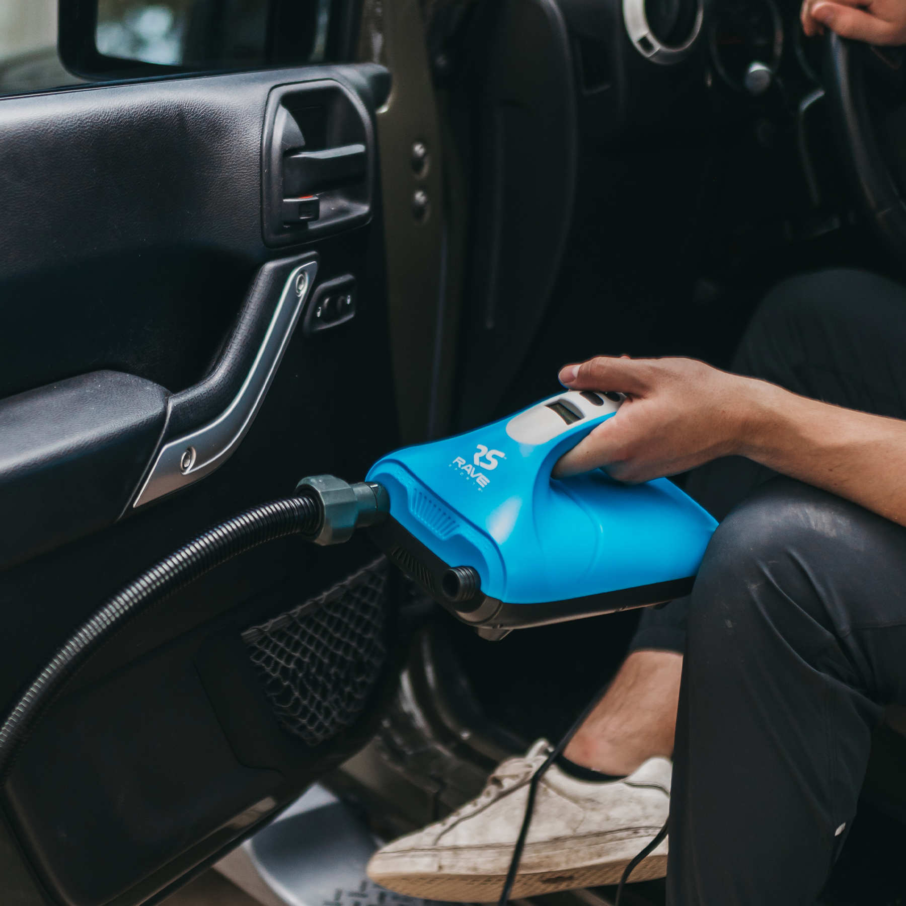 a man holding Rave Rapid Dual Stage 12VDC inflator while inside the car