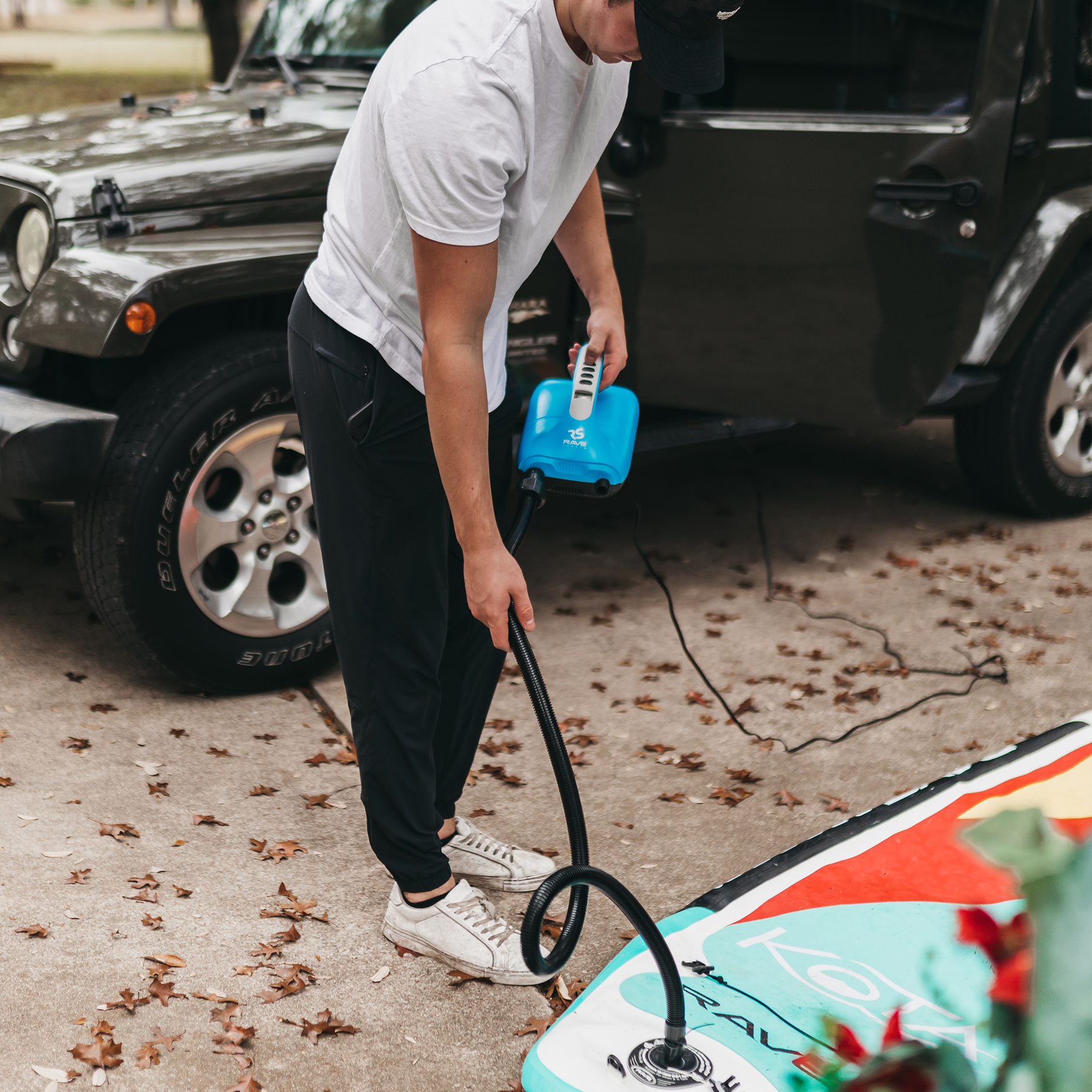 A man inflating SUP using Rave Rapid Dual Stage 12VDC inflator