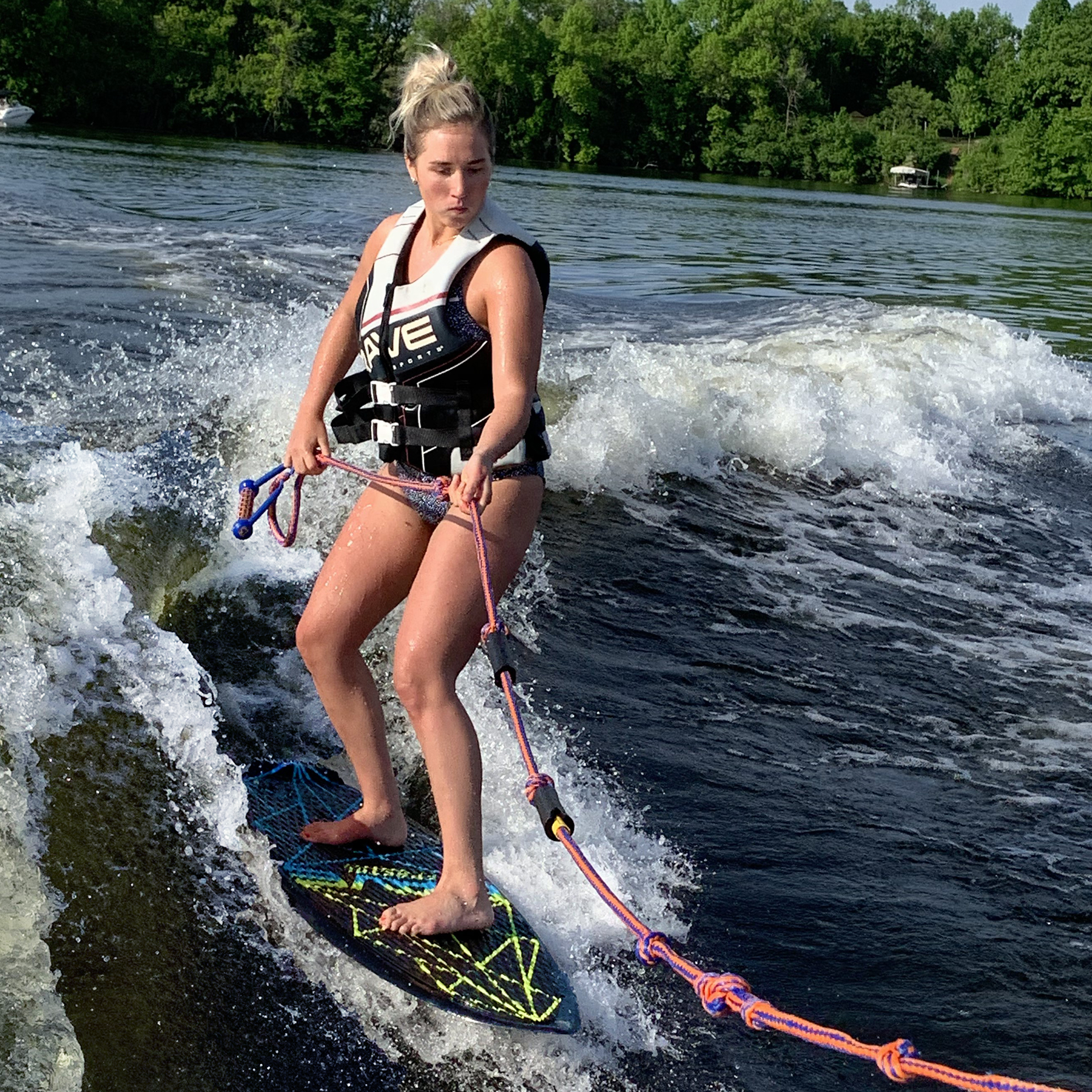 Rave Sports Fractal Wake Surf Board with a girl riding on it.