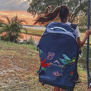 A girl wearing Pulse The Honey 10'6" Backpack and holding Pulse Paddle