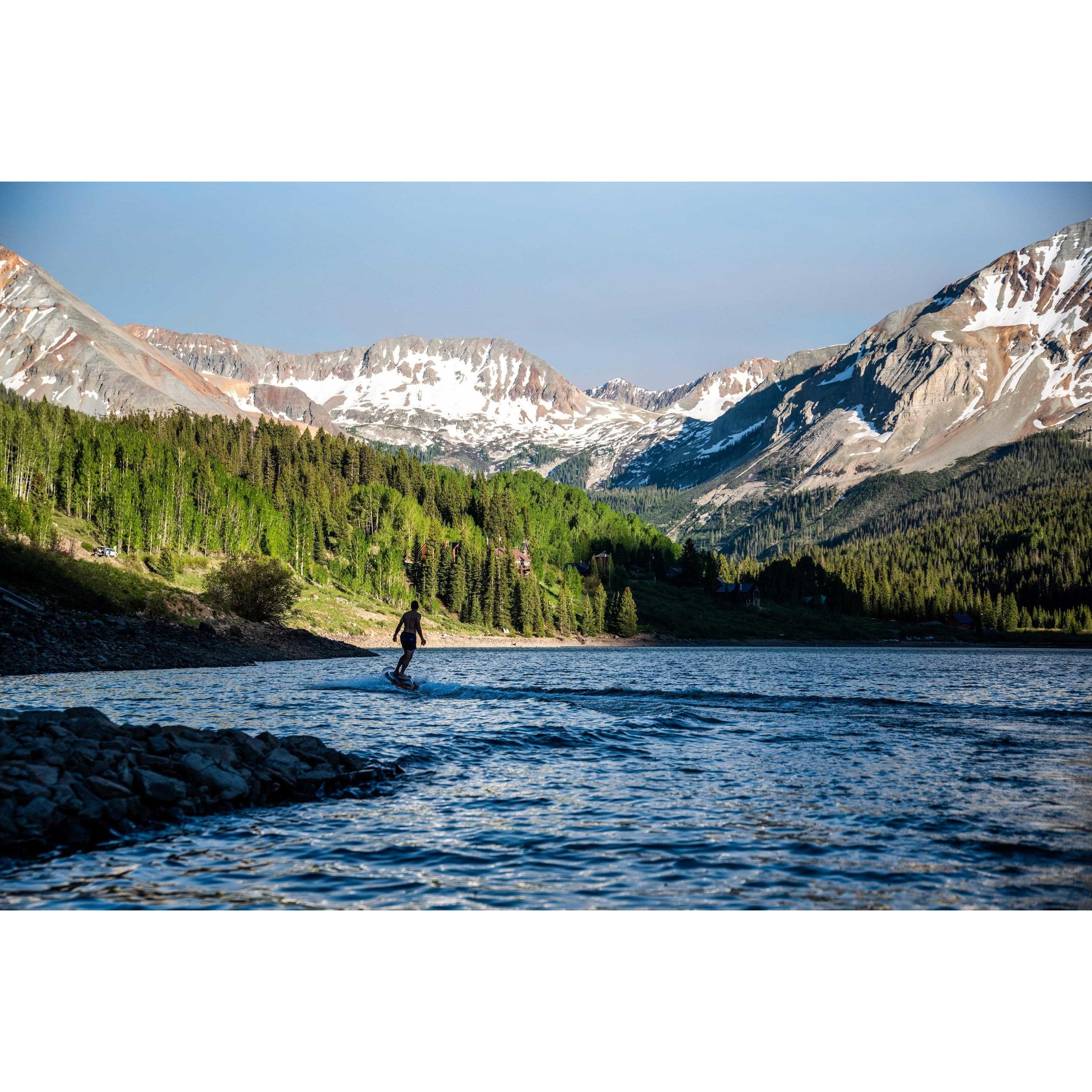 Man riding Yujet Electric Surfobard EJB-01 with a mountain view