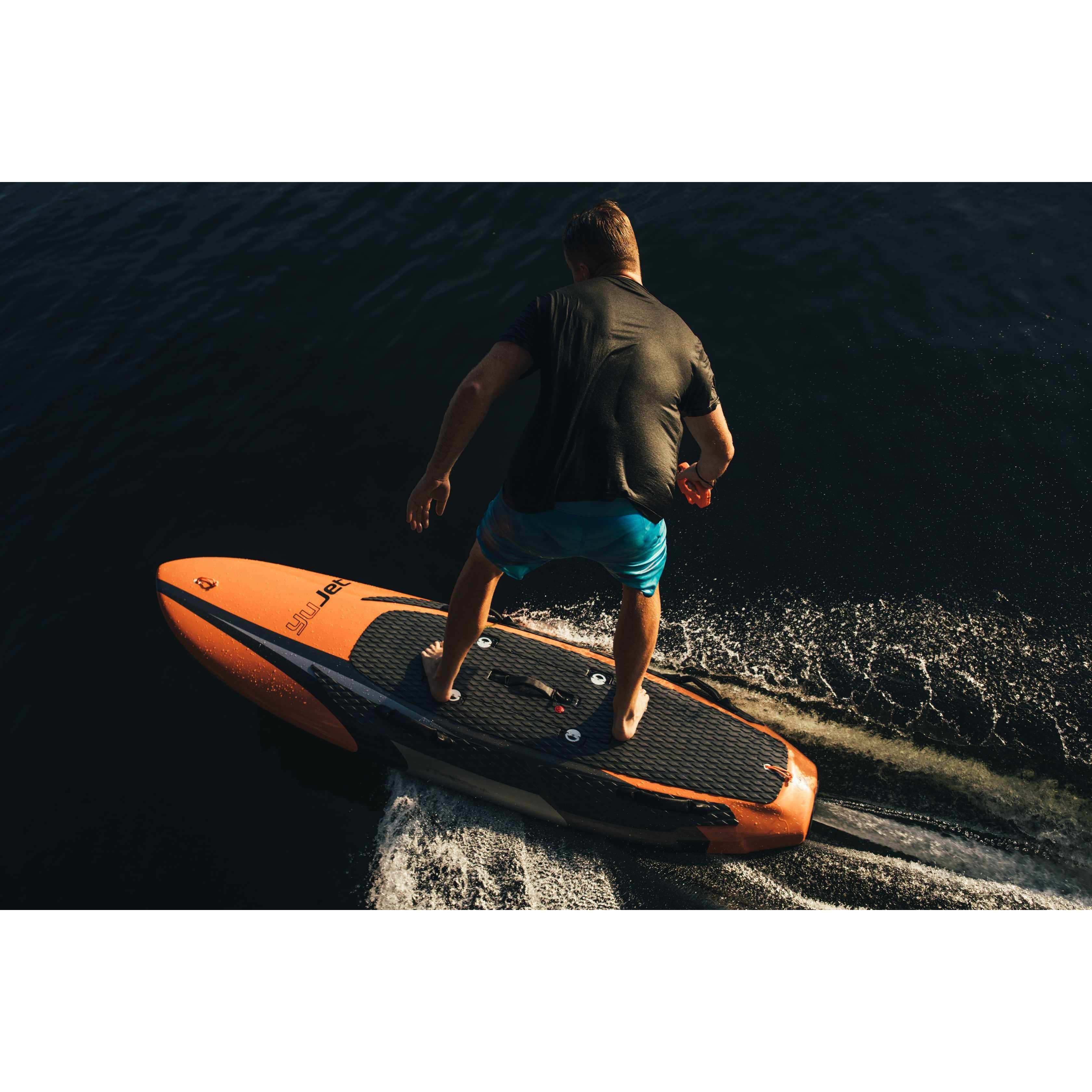 Back view of a man in a black shirt riding Yujet Electric Surfobard EJB-01 