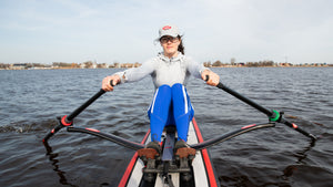 Woman rowing RowOnAir board with the ROWONAIR RowMotion Universal Rowing Unit