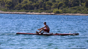 Man rowing on the ROWONAIR Mojo 18' Inflatable Paddle Board with RowOnAir Universal Rowing Unit