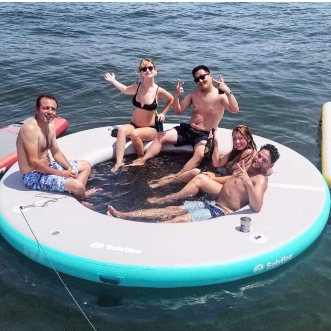 Platform - 5 people relaxing on  the Solstice Watersports Inflatable 8' X 8' X 8" Circular Mesh Dock 