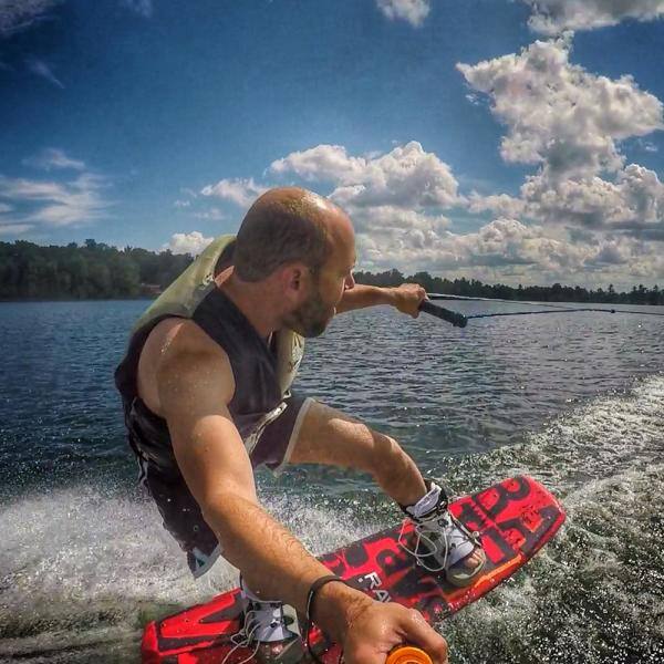 A man wakeboarding with Rave Lyric Red Wakeboard with RAVE boots