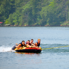 Load image into Gallery viewer, Rave Rush 4P Towable Tube being towed with 4 people riding on it