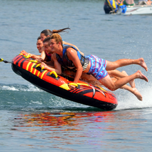 Load image into Gallery viewer, Rave Sports Rush 4P Towable Tube being towed with 4 people riding on it