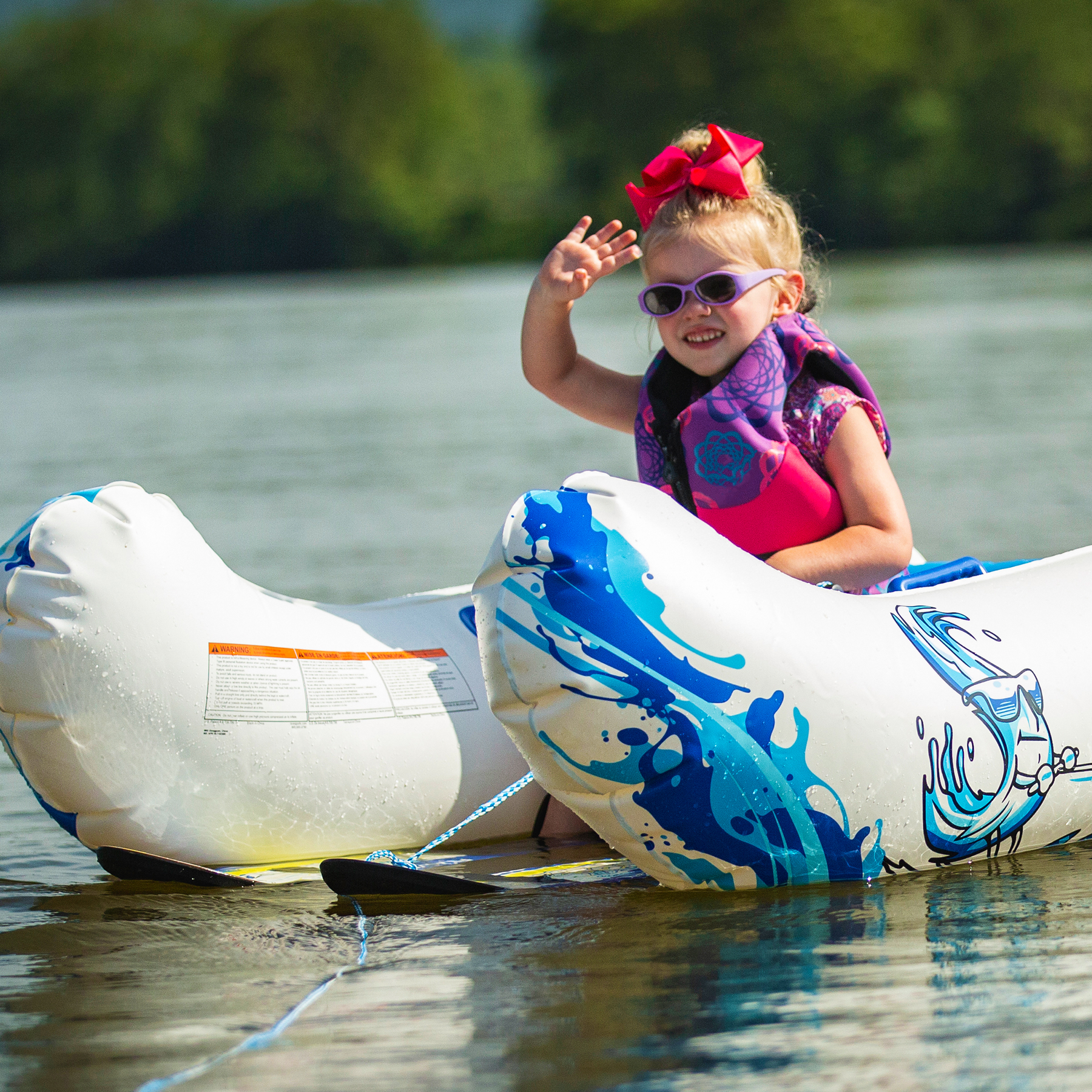 A kid riding in Rave Aqua Buddy while getting ready to ski with Rave Steady Eddy Trainer Water Ski'