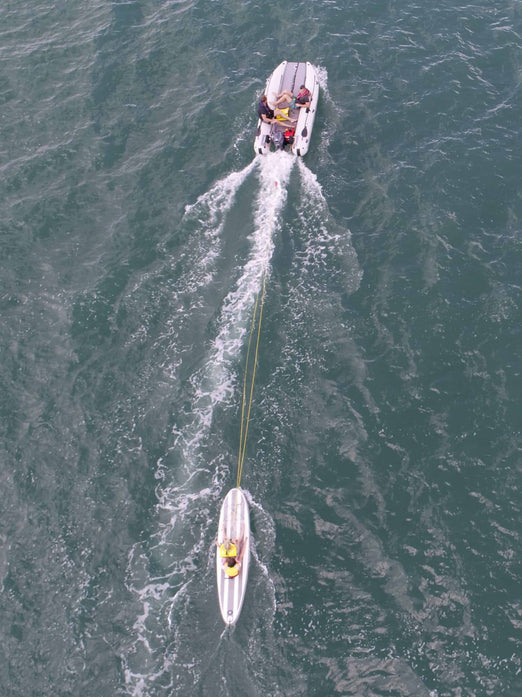 People on board the Takacat T460LX Inflatable Boat with a paddleboard behind