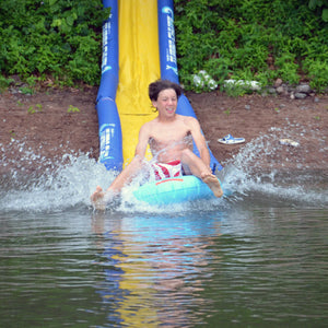 boy riding the turbo water sled sliding from the Rave Sports 116' Turbo Chute Package 02971-12 in to the lake .