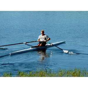 Boats -Man rowing on Little River Marine Olympus Rowing Shell on calm water.